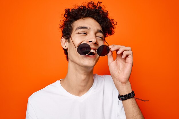 Cheerful guy in a white tshirt dark glasses fashion orange background high quality photo