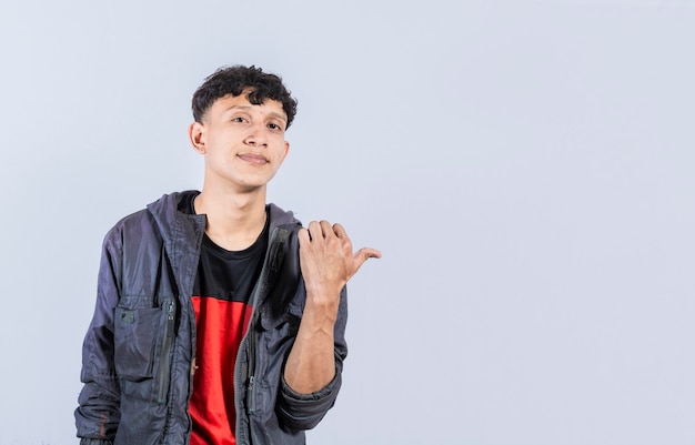 Cheerful guy with a friendly smile shows you the direction to a nice place friendly guy pointing his thumb to the right young man pointing at a banner to the side