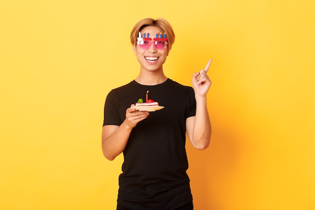 Cheerful, handsome asian birthday guy in funny sunglasses