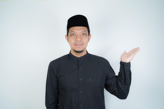 Cheerful handsome Asian Muslim man pointing hand finger at empty space for advertising on
