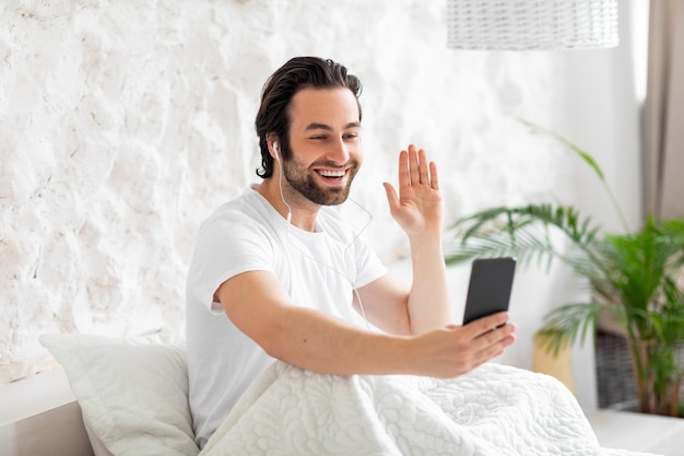 Cheerful handsome guy having video call in the morning