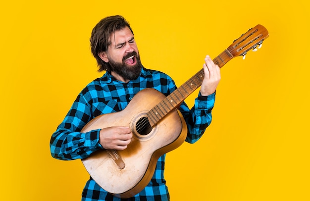 Веселый красивый мужчина-гитарист играет на гитаре и поет песню страны, музыку.