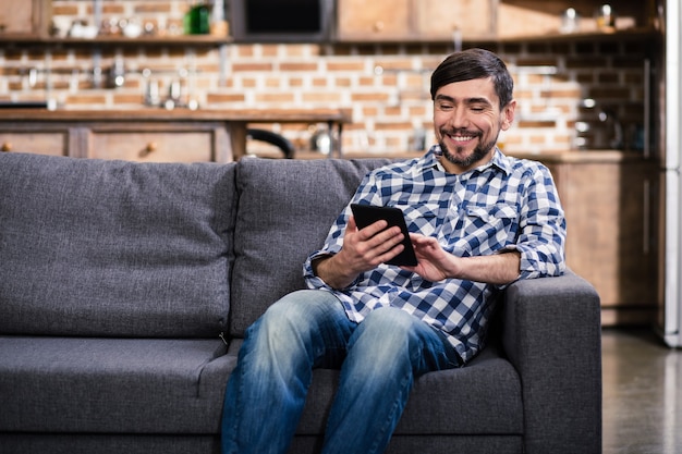 Cheerful handsome man holding an a book while sitting at home