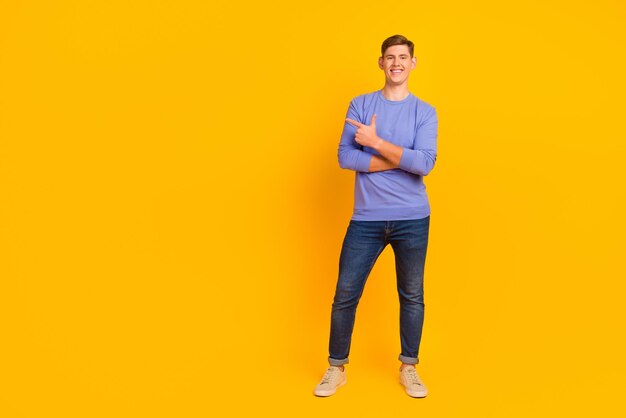 陽気なハンサムな男が明るい色の背景に指を指して方向を示しています