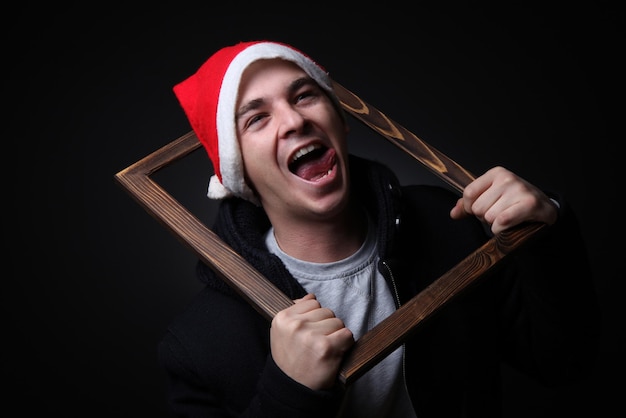 Cheerful handsome young adolescent male in santa costume on black background.