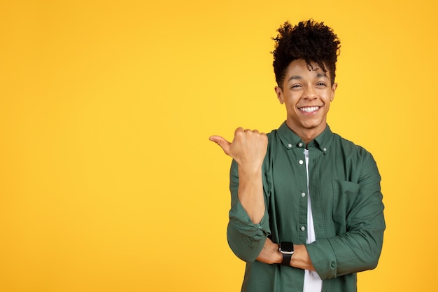 Cheerful handsome young black guy pointing at copy space