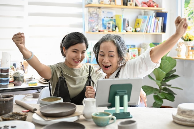 Cheerful and happy asian aged woman and young woman in the pottery workshop together