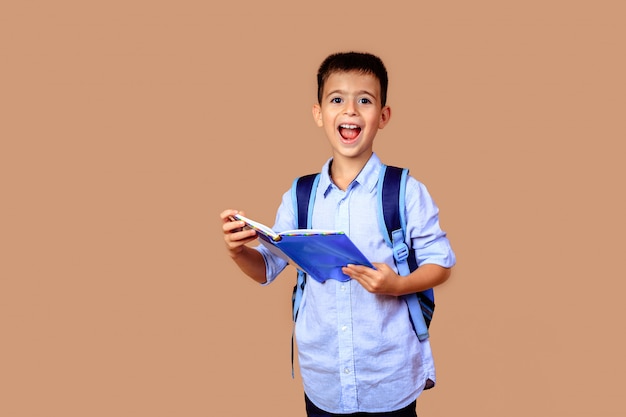 Cheerful happy boy schoolboy with books in hands and backpack