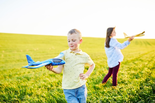 Cheerful and happy children play in the field and imagine themselves to be pilots on a sunny summer day Kids dreams of flying and aviation