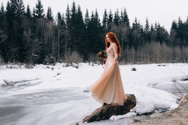 Cheerful and happy girl bride stands in the snow