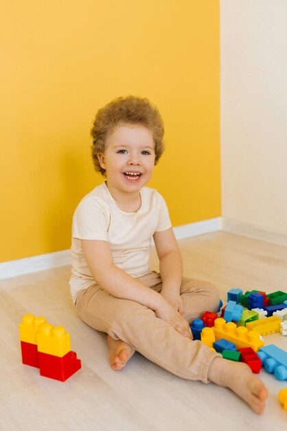 Cheerful happy kid is playing with toys a boy builds a construction kit at home spending time