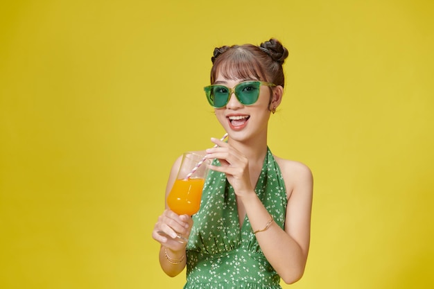 Cheerful happy pretty young woman hold hands cocktail on yellow color background