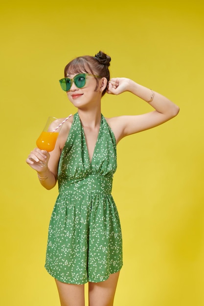 Cheerful happy pretty young woman hold hands cocktail on yellow color background