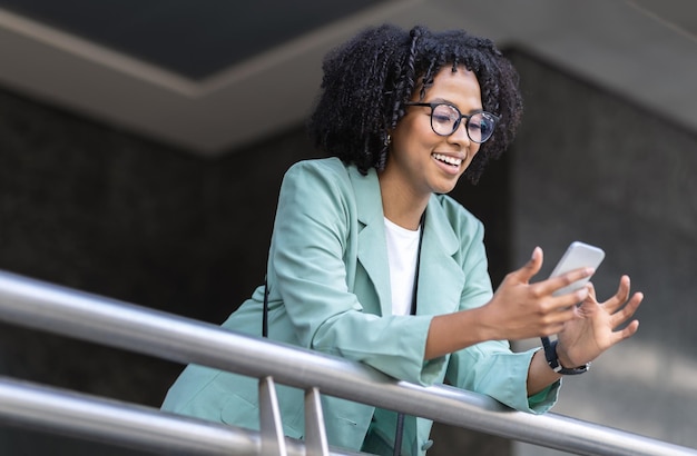 Photo cheerful happy young black businesswoman using cell phone at office