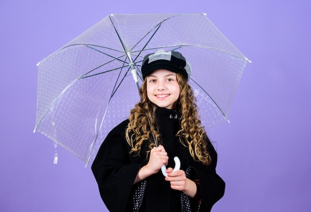 Cheerful hipster child in positive mood rain protection Rainbow autumn fashion happy little girl with transparent umbrella little girl in french beret and coat Feeling free and relaxed