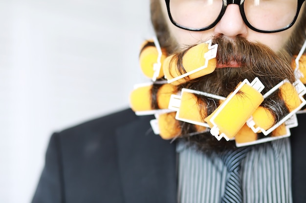 Cheerful hipster man with curlers in a beard. Surprised man with glasses looks in front.