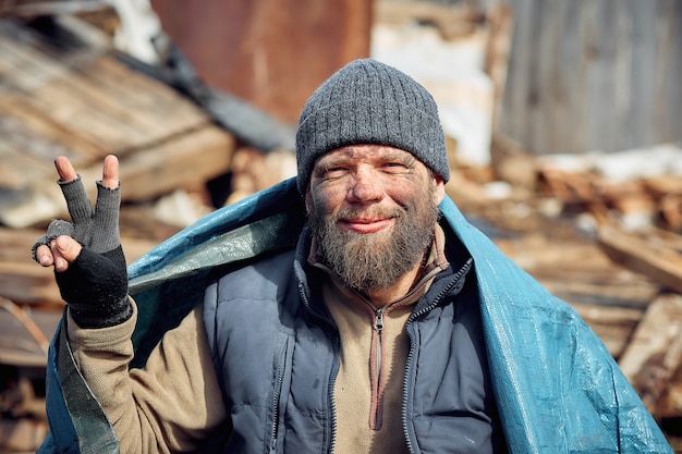 A cheerful homeless and unemployed man in the ruins