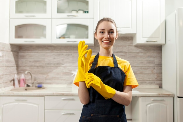 cheerful housekeeper in apron and gloves cleans at home and smiles woman housewife in uniform