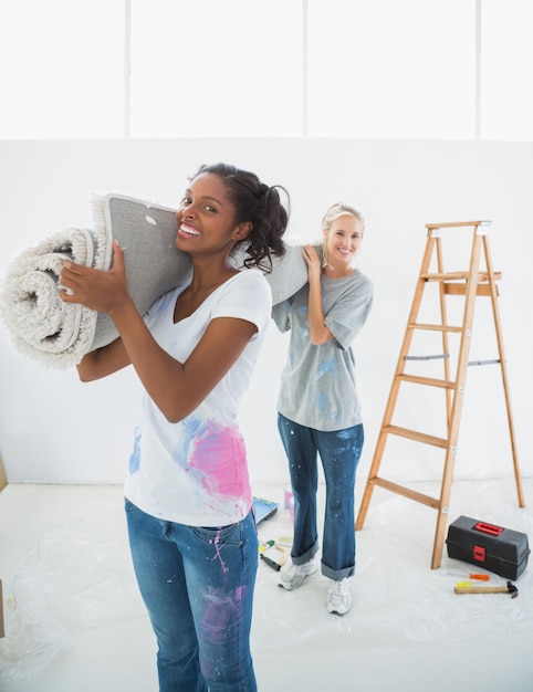 Photo cheerful housemates carrying rolled up rug