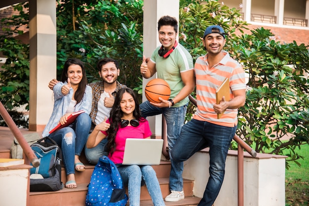 쾌활한 인도 아시아 젊은 대학생 또는 친구가 앉아, 서 있거나 캠퍼스에서 걷는 동안 함께 웃고 그룹