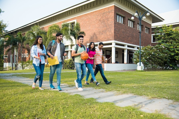 Cheerful Indian asian young group of college students or friends laughing together while sitting, standing or walking in campus