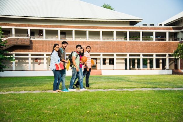 Cheerful Indian asian young group of college students or friends laughing together while sitting, standing or walking in campus