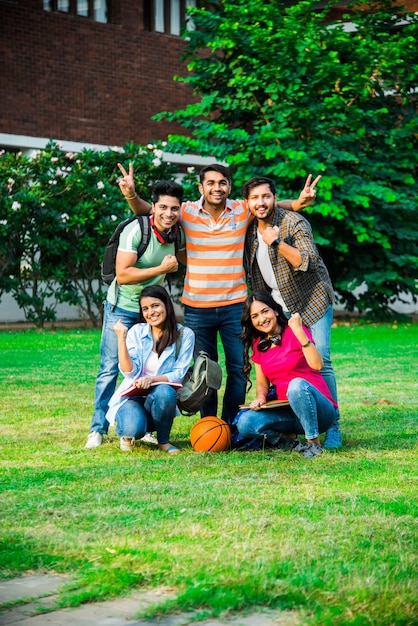 Cheerful Indian asian young group of college students or friends laughing together while sitting, standing or walking in campus