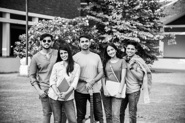 Cheerful Indian asian young group of college students or friends laughing together while sitting, standing or walking in campus