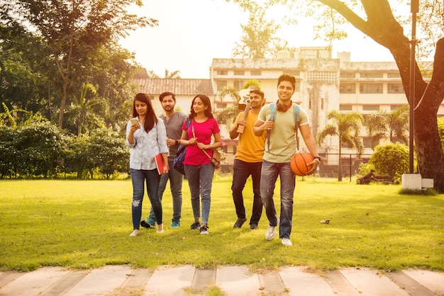 Cheerful Indian asian young group of college students or friends laughing together while sitting, standing or walking in campus