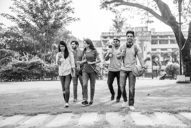 Cheerful Indian asian young group of college students or friends laughing together while sitting, standing or walking in campus