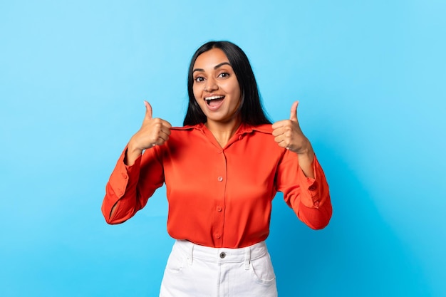 Cheerful indian lady giving thumbs up standing on blue background