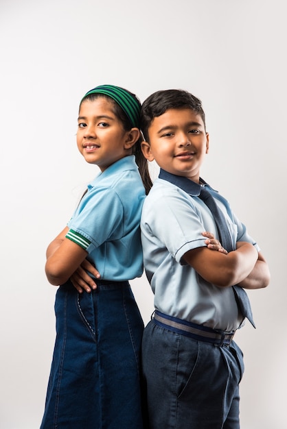 Cheerful Indian school kids in uniform standing isolated over white background