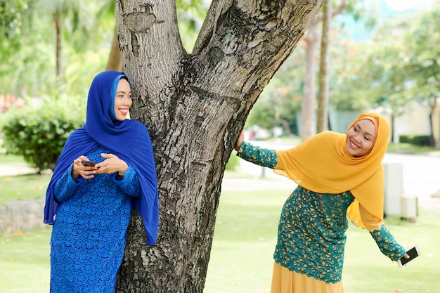 Cheerful islamic women playing in park