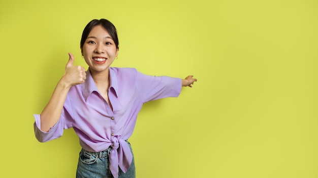 Femmina giapponese allegra che fa gesti con i pollici in su su sfondo giallo panorama