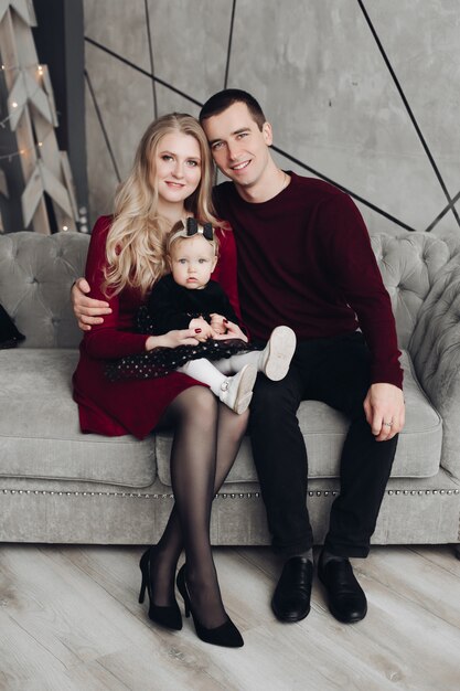 Cheerful and jovial family with baby on gray sofa