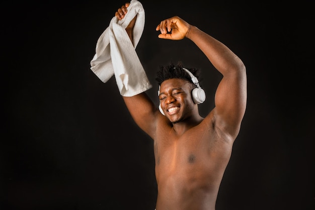 cheerful joyful african man in headphones with towel