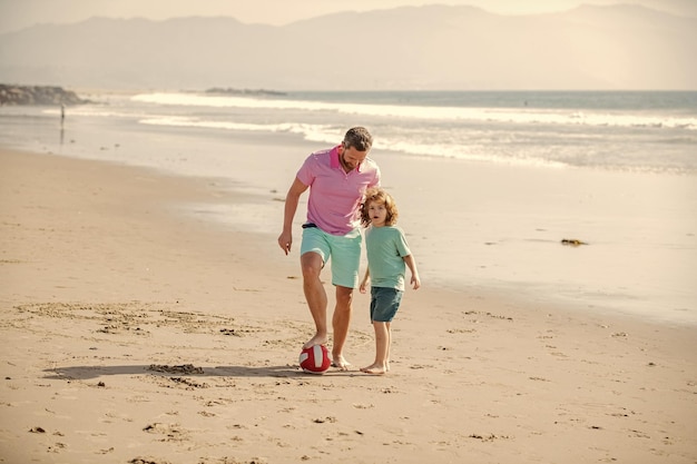 Bambino allegro e papà che corrono sulla spiaggia durante le vacanze estive con l'amicizia della palla