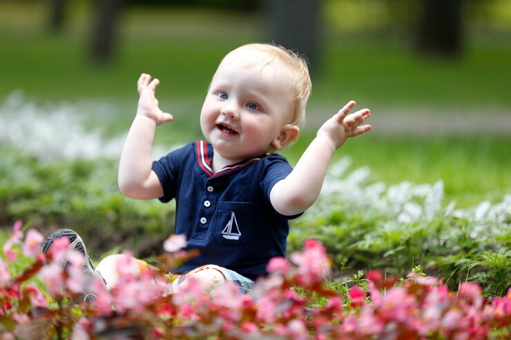 Cheerful kid on the grass claps his hands