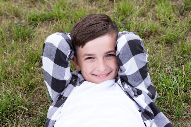 Cheerful kid resting on meadow