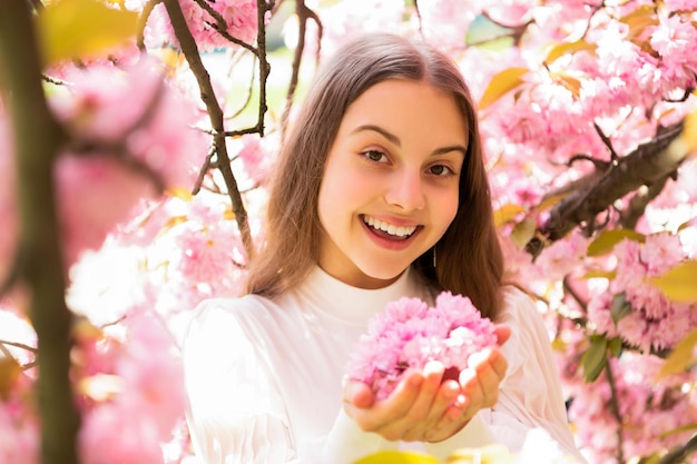Cheerful kid at sakura flower bloom in spring