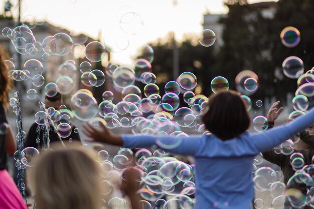 Foto bambini allegri che giocano in mezzo alle bolle sulla strada