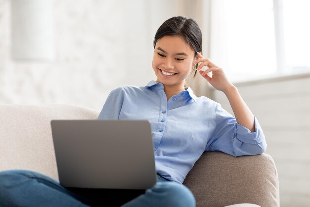 Cheerful korean woman chilling at home using computer