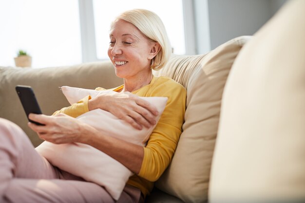 Cheerful lady reading message on phone