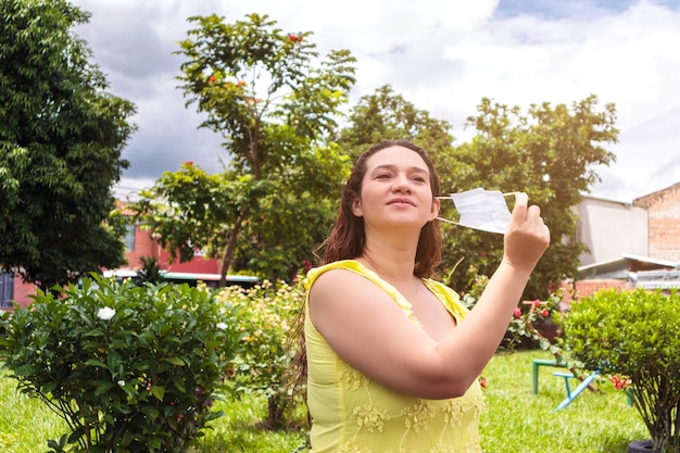 cheerful Latin woman removing her mask for the end of the pandemic