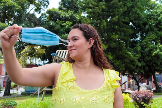 cheerful Latin woman removing her mask for the end of the pandemic