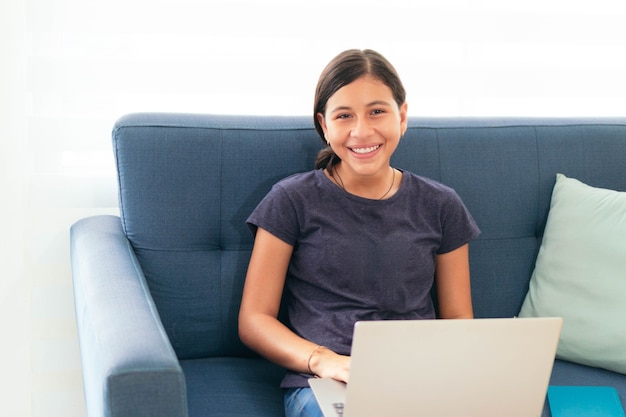 Ragazza studentessa latina allegra che ride con il computer portatile a casa