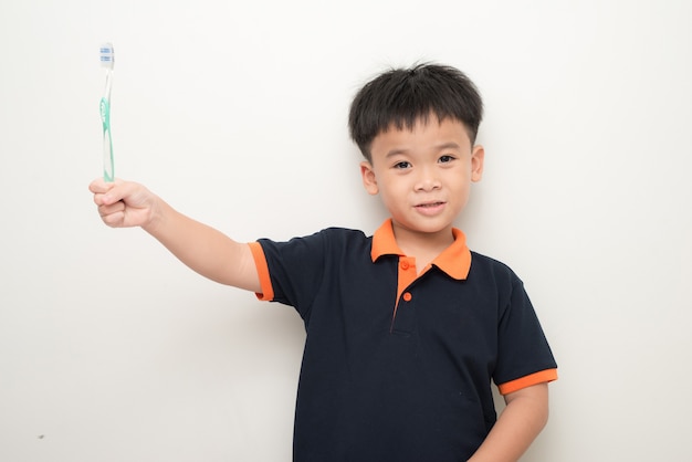 Cheerful little boy holding a tooth brush over white background, Studio portrait of a healthy mixed race boy with a toothbrush isolated.