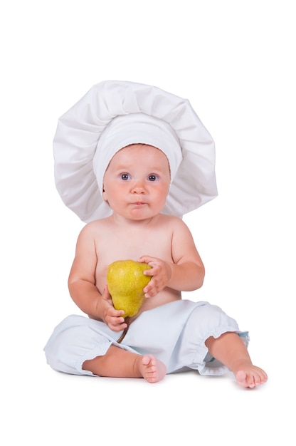 Cheerful little child with a pear in his hands in a chef suit on a white.