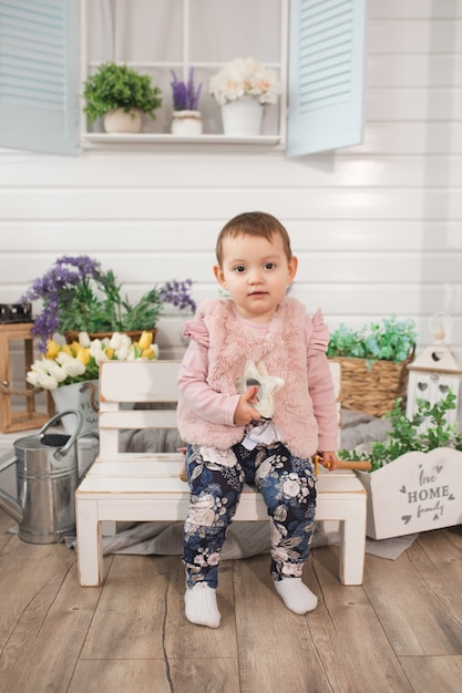 cheerful little girl child one year old sits on bench on veranda spring summer time nature pastime concept