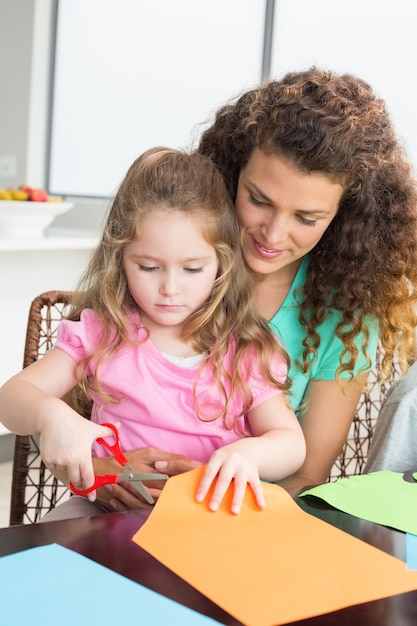 Carta di taglio bambina allegra con madre al tavolo